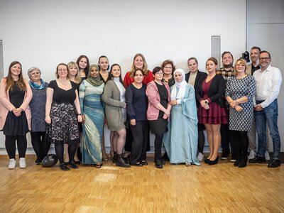 Das Foto zeigt Absolventinnen und Absolventen der einjährigen Ausbildung zur/m Pflegefachhelfer*in zusammen mit dem Team der UKA